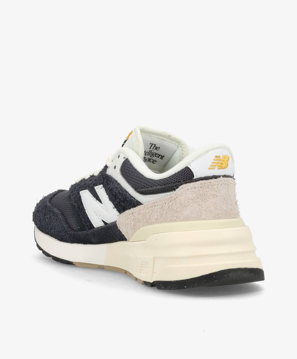 Sort og hvid sneaker med New Balance-logo på siden og hælen, set fra en vinkel bagfra. Skoen har en tyk, hvid sål og beige detaljer.