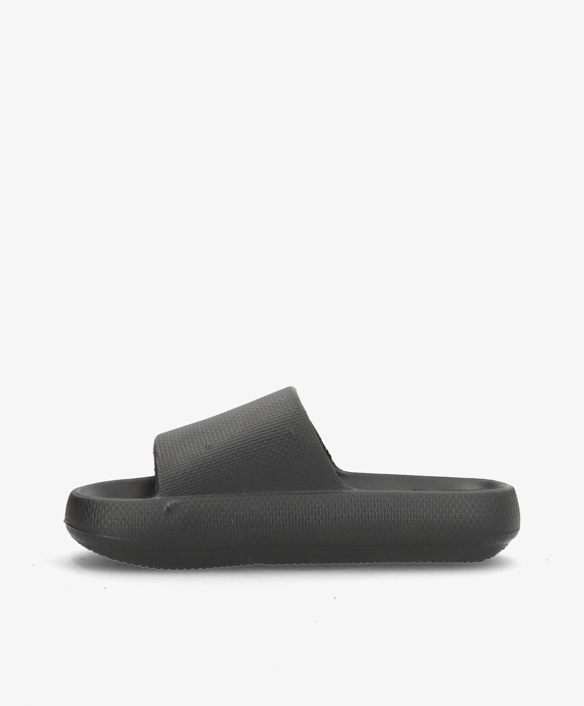 Sort slip-in sandal med tyk sål og bred rem, set fra siden mod en hvid baggrund.