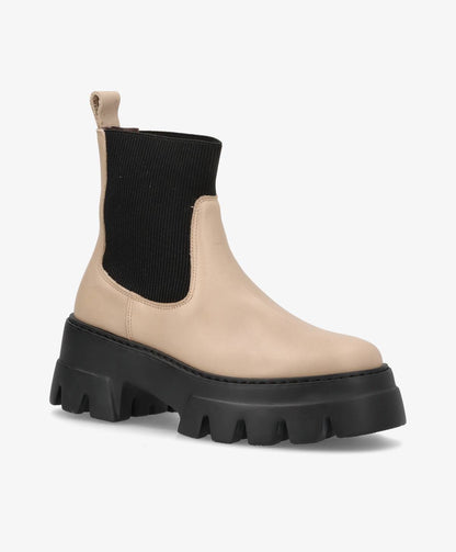 Beige støvle med sort elastisk skaft og tyk sort sål.
