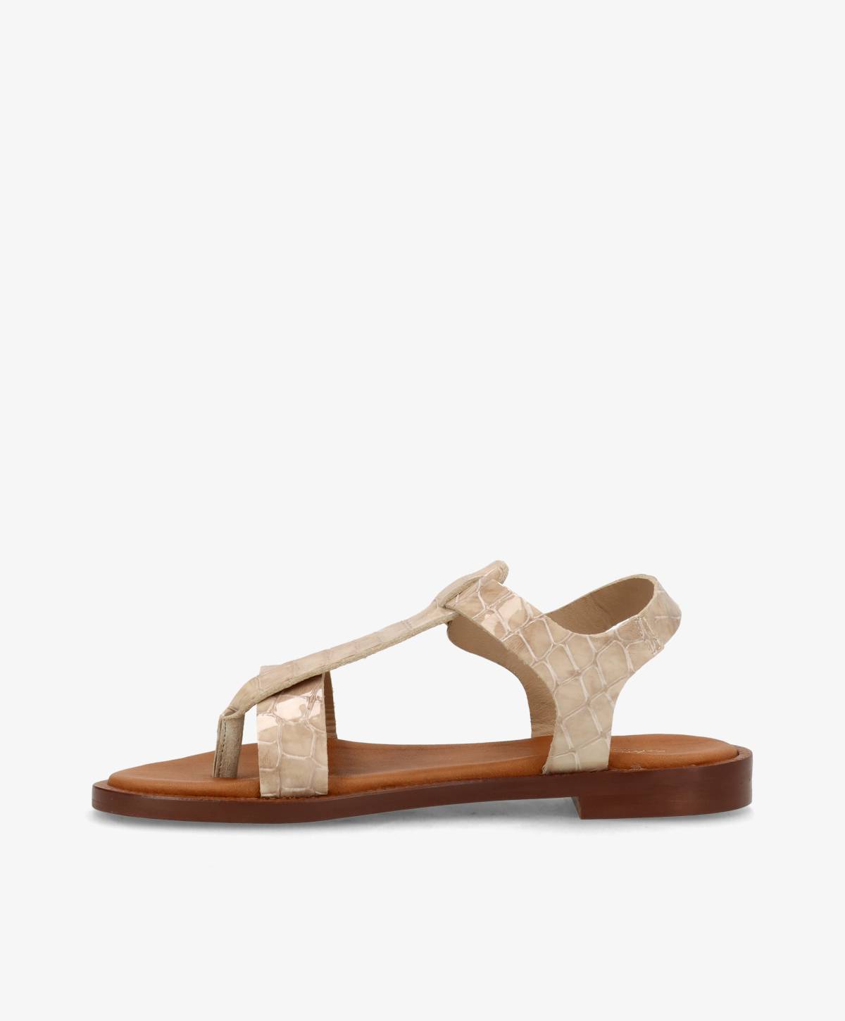 Beige sandal med krokodillemønster og flad brun sål, set fra siden.