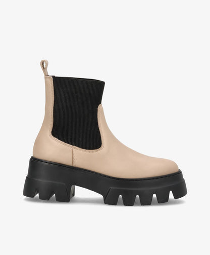 Beige støvle med sort elastisk ankel og tyk sort sål.