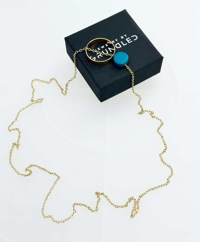 Guldbelagt halskæde fra Grundled med blå træperle og en rund, hul guldperle.