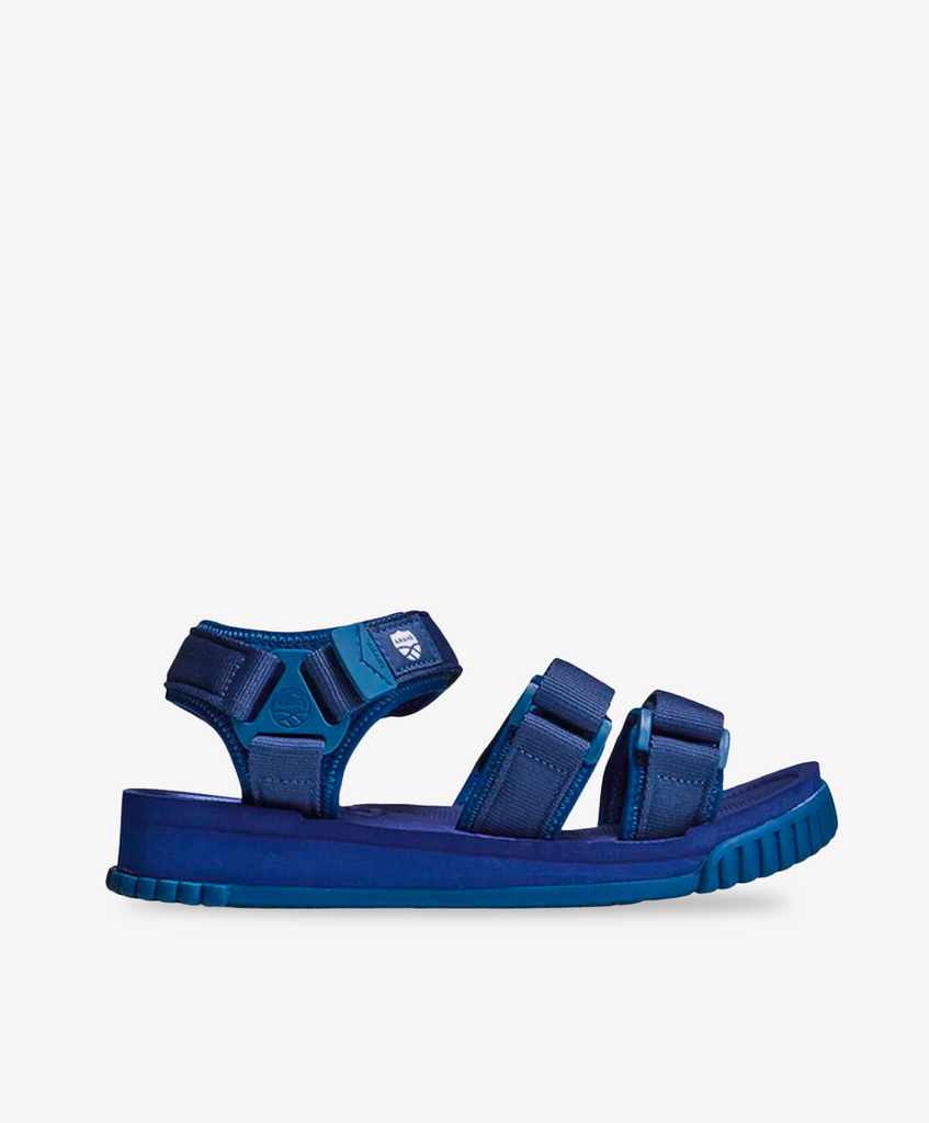 Blå Shaka sandaler med justerbare velcroremme. 